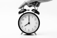 A classic black and white alarm clock being held by a hand, depicting the concept of time.